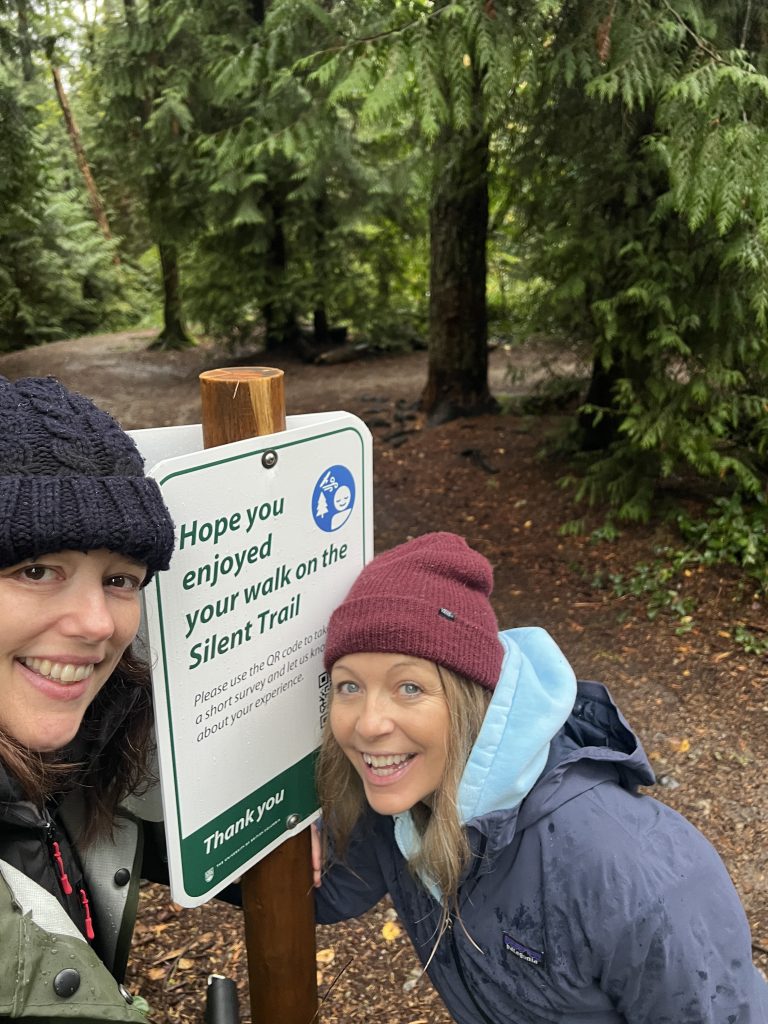 Dr. Tara Tiger Brown and Megan Lammam next to a Silent Trails sign.